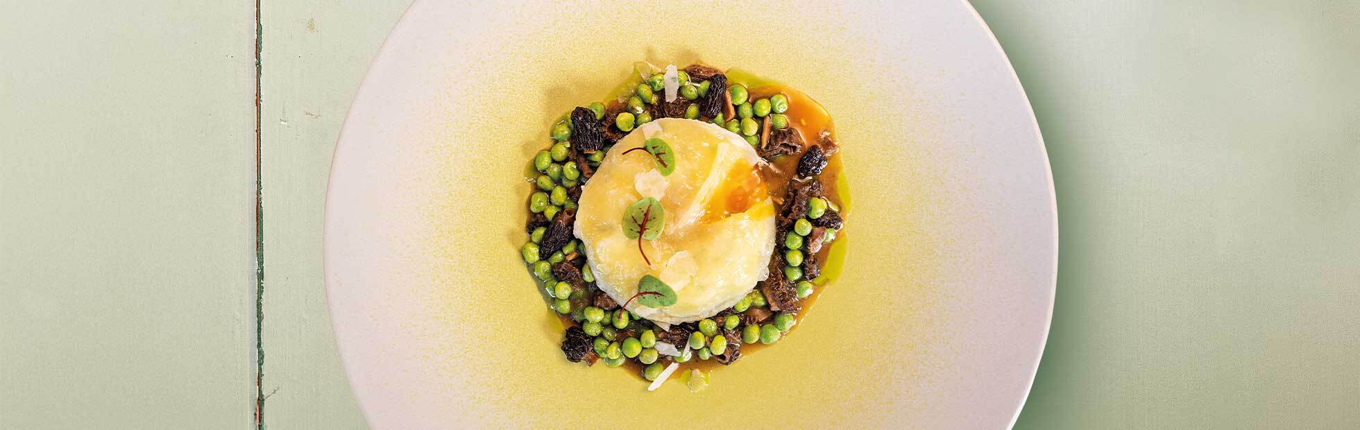 Potato ravioli filled with soft egg yolk and ricotta on a pea and morel ragout