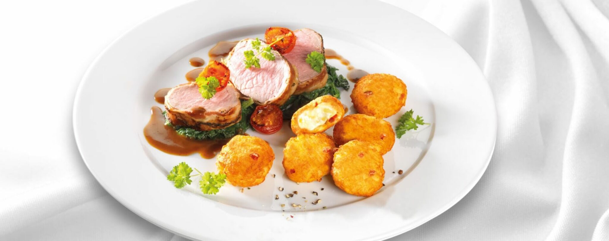 11er Rösti-Bergkäse Schmankerl mit Kalbsfilet im Speckmantel auf Blattspinat und Apfel-Balsamico-Jus