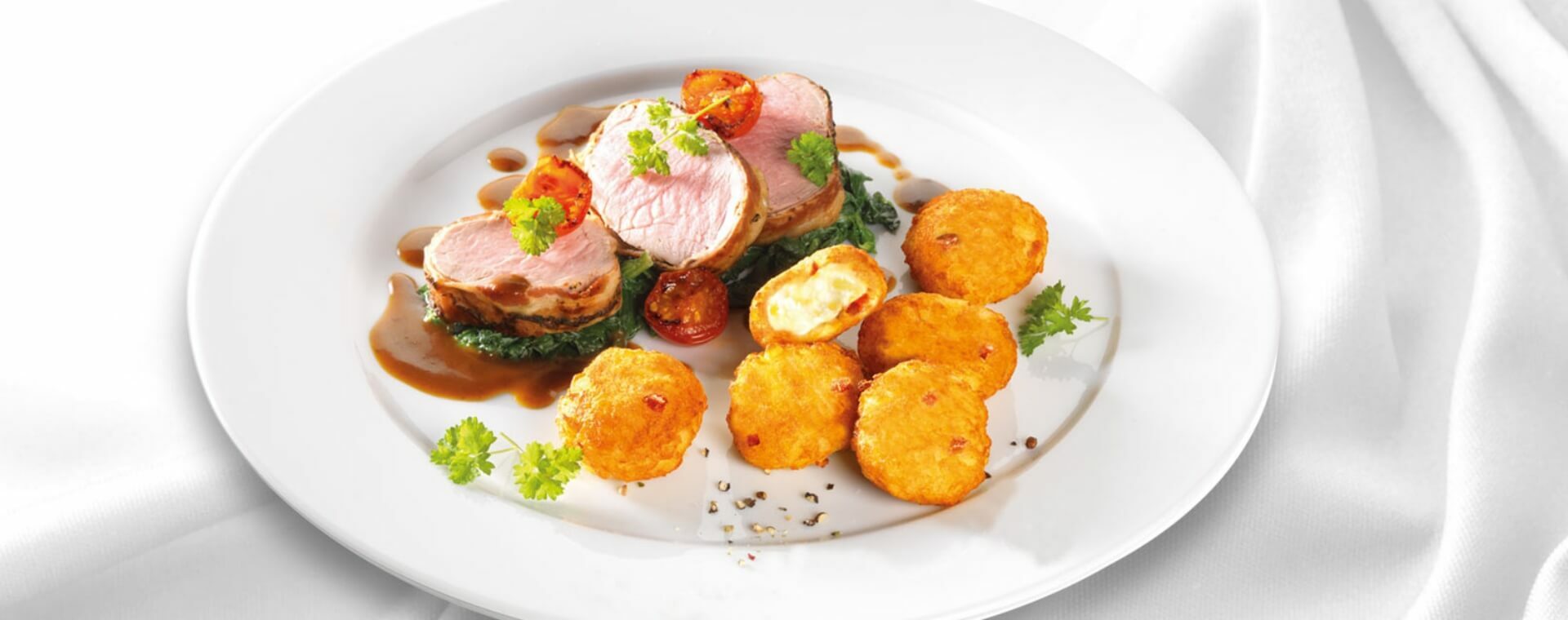 11er Rösti-Bergkäse Schmankerl mit Kalbsfilet im Speckmantel auf Blattspinat und Apfel-Balsamico-Jus