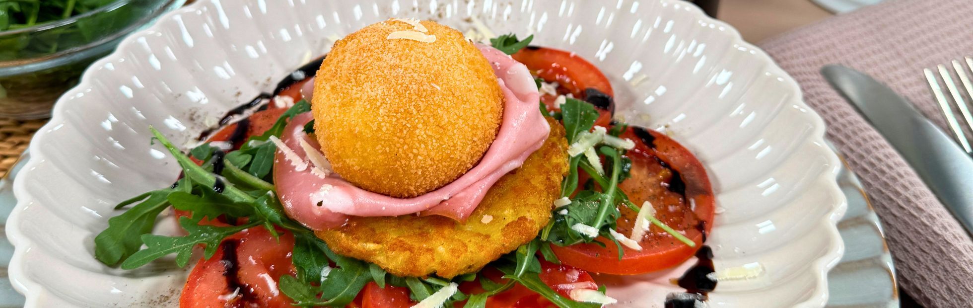 Rösti croccanti con burrata impanata su pomodori marinati, mortadella e rucola